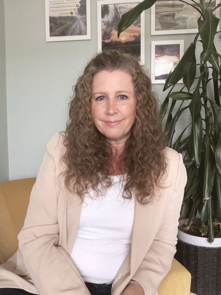 Ally — counsellor and psychotherapist, seated calmly in her sage-green therapy room